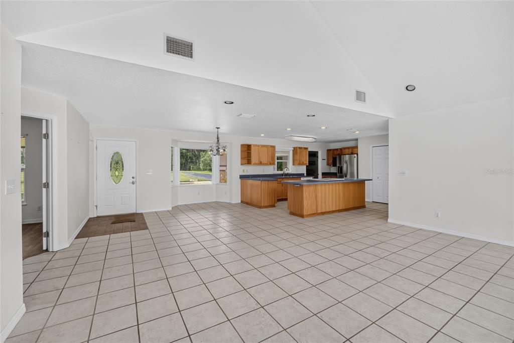 A bright living room with vaulted ceilings, a sectional sofa, and views of a pool — 19785 NW 123RD COURT, MICANOPY, FL