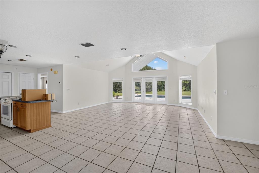 An open-concept living area features a kitchen with wood cabinets, a central island, and tile flooring — 19785 NW 123RD COURT, MICANOPY, FL