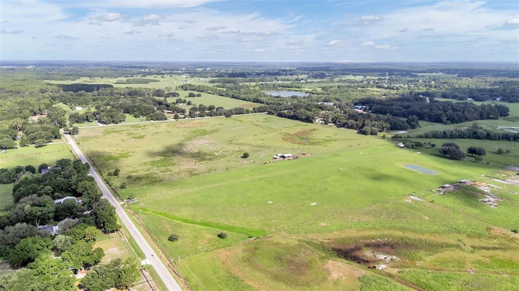 An aerial view shows a large, grassy rural property with a road and small structures — 4025 W BELLA VISTA STREET, LAKELAND, FL
