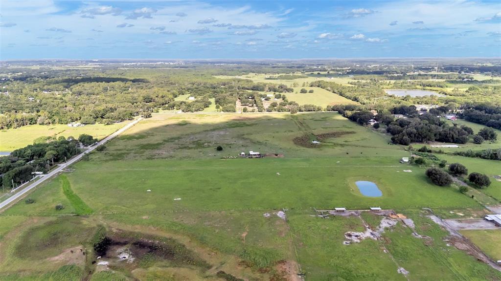 An aerial view shows a large, open pasture with a small pond and a barn — 4025 W BELLA VISTA STREET, LAKELAND, FL