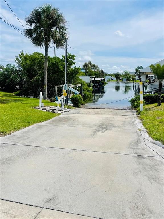A concrete boat ramp leads into a canal surrounded by grass and a palm tree — 160 NEW YORK STREET, PALMETTO, FL