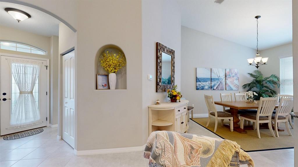 A living room with a vaulted ceiling, ceiling fan, and open kitchen with bar seating — 107 PARK PLACE CIRCLE, PALM COAST, FL