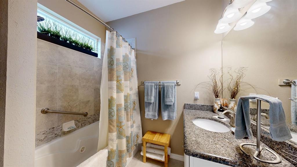 A kitchen features white cabinetry, granite countertops, a stainless steel refrigerator, and a breakfast bar — 107 PARK PLACE CIRCLE, PALM COAST, FL