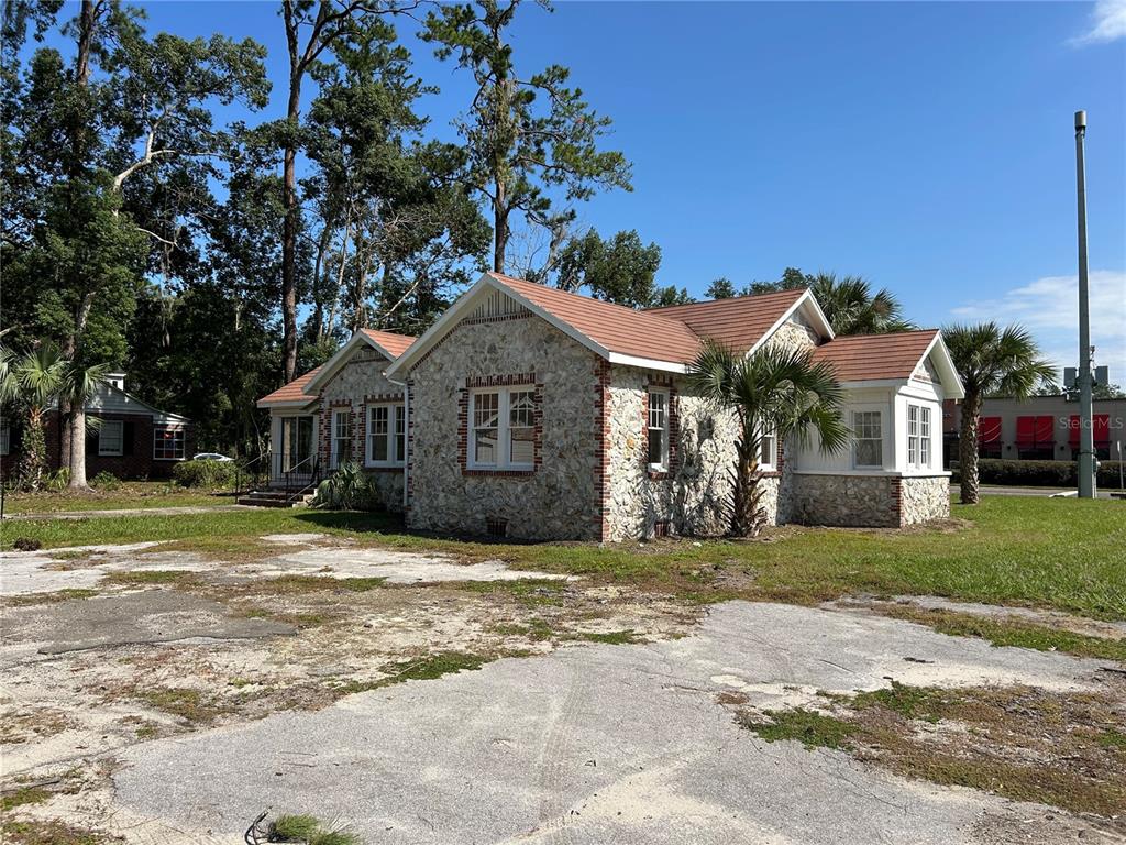 A stone-faced house with a red shingled roof and two palm trees in the front yard — 1008 NW 13TH STREET, GAINESVILLE, FL