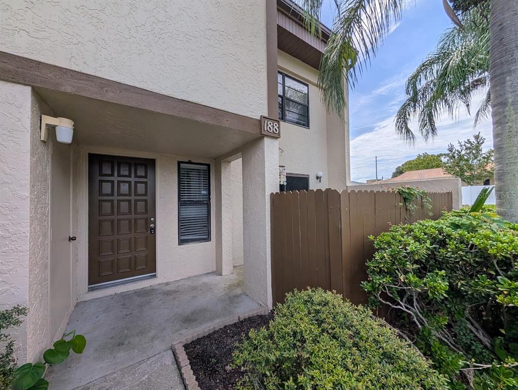 A brown front door is recessed under a covered entryway next to a wooden fence — 9209 SEMINOLE BOULEVARD UNIT 188, SEMINOLE, FL