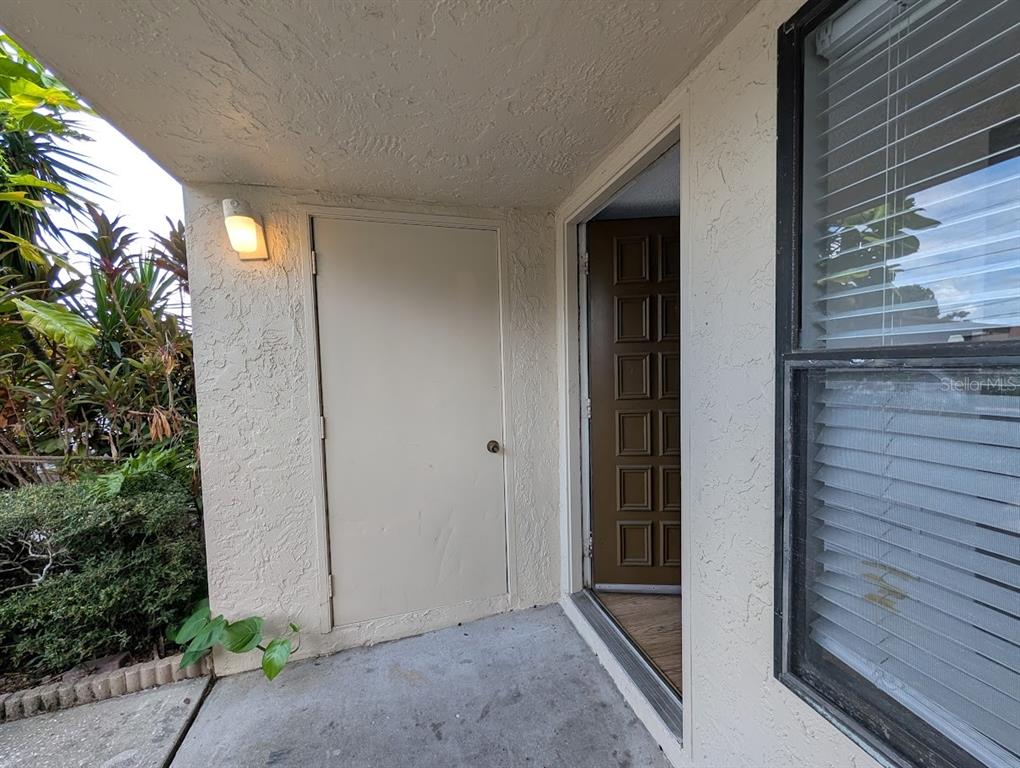A beige exterior wall features a storage closet door next to an open front door — 9209 SEMINOLE BOULEVARD UNIT 188, SEMINOLE, FL