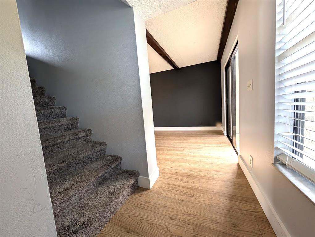 A carpeted staircase leads upward next to a room with wood-look flooring and dark walls — 9209 SEMINOLE BOULEVARD UNIT 188, SEMINOLE, FL