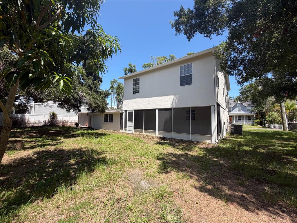 A two-story house with a screened-in porch and a large, grassy backyard — 7405 S DESOTO STREET, TAMPA, FL