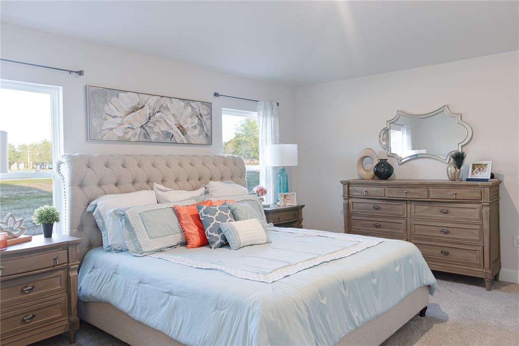 A bedroom features a tufted headboard, light blue bedding, and matching wooden furniture — 3312 NE CAITLIN LANE, BELL, FL