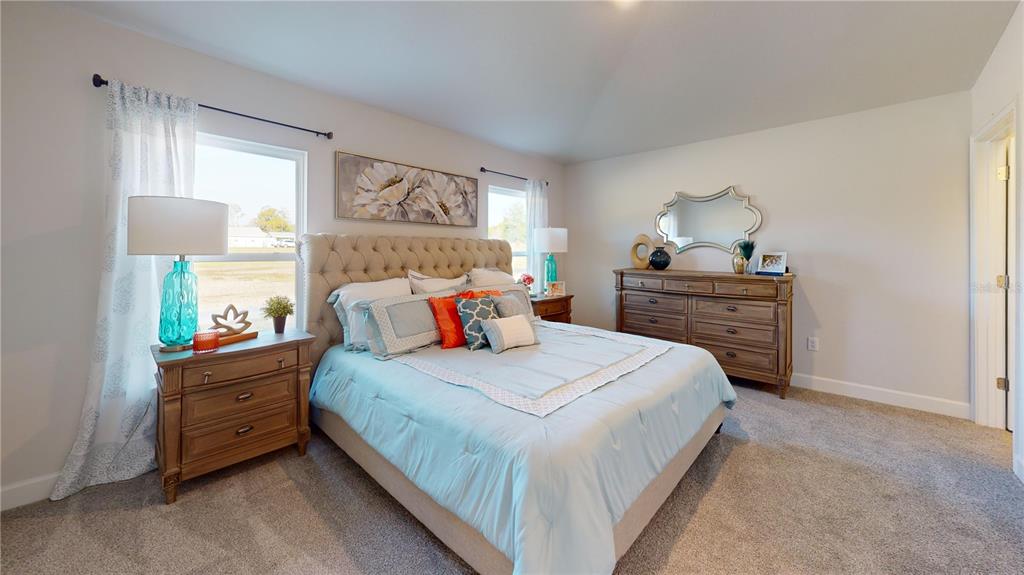 A bedroom features a tufted headboard, light blue bedding, wooden furniture, and two windows — 3312 NE CAITLIN LANE, BELL, FL