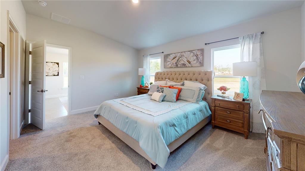 A bedroom features a tufted headboard, light blue bedding, two nightstands, and two windows — 3312 NE CAITLIN LANE, BELL, FL