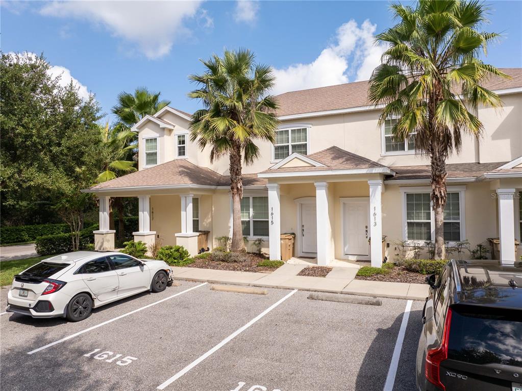 A two-story townhouse exterior with a parking lot and palm trees in front — 1615 RETREAT CIRCLE, CLERMONT, FL