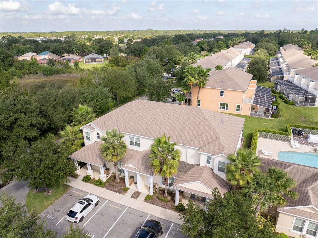 An aerial view shows a multi-unit residential building with a parking lot and swimming pool — 1615 RETREAT CIRCLE, CLERMONT, FL
