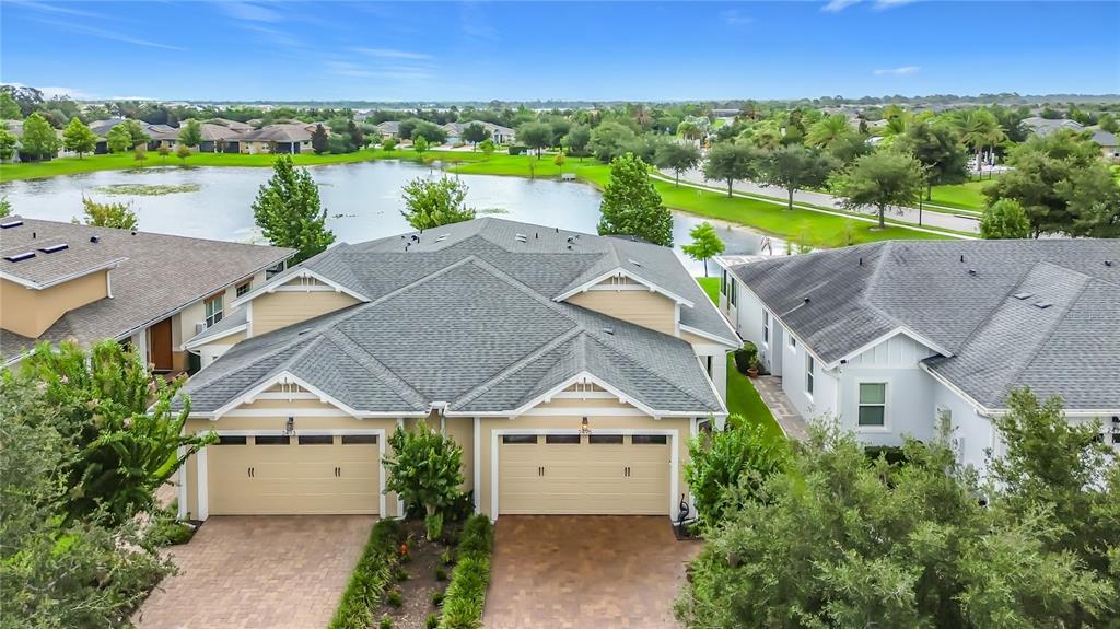 An aerial view shows a duplex home with two garages and a lake in the background — 2495 DATURA LOOP, ST CLOUD, FL
