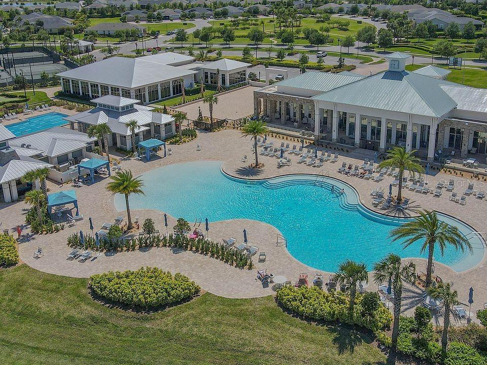 An aerial view of a community swimming pool complex with lounge chairs and surrounding buildings — 2495 DATURA LOOP, ST CLOUD, FL