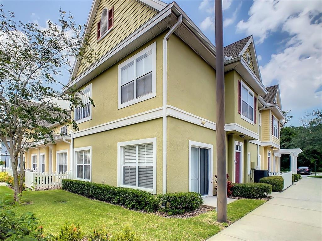 A two-story yellow townhouse with white trim, a sliding glass door, and manicured hedges — 4006 SANTA MARIA DRIVE UNIT 108, KISSIMMEE, FL