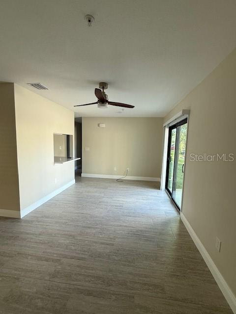An open living area features light-colored tile flooring, a ceiling fan, and sliding glass doors — 140 HUNTER LAKE DRIVE UNIT B, OLDSMAR, FL