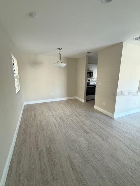 An empty dining area features light-colored wood-look flooring and a modern pendant light fixture — 140 HUNTER LAKE DRIVE UNIT B, OLDSMAR, FL