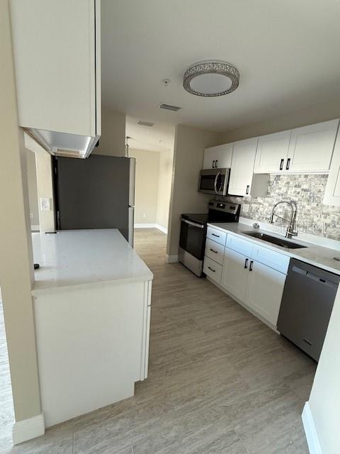 A kitchen features white cabinets, stainless steel appliances, a tiled backsplash, and light wood-look flooring — 140 HUNTER LAKE DRIVE UNIT B, OLDSMAR, FL