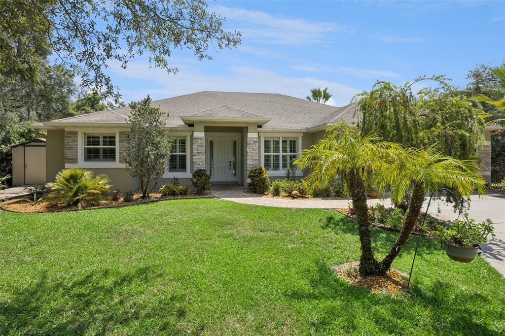 A single-story house with a stone-accented facade, a paved walkway, and a landscaped front lawn — 11540 NELLIE OAKS BEND, CLERMONT, FL