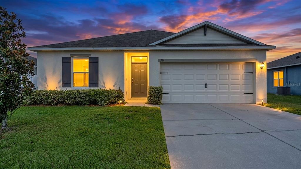 A single-story house with a white stucco exterior, a two-car garage, and a front lawn — 524 BURNHAM CIRCLE, AUBURNDALE, FL