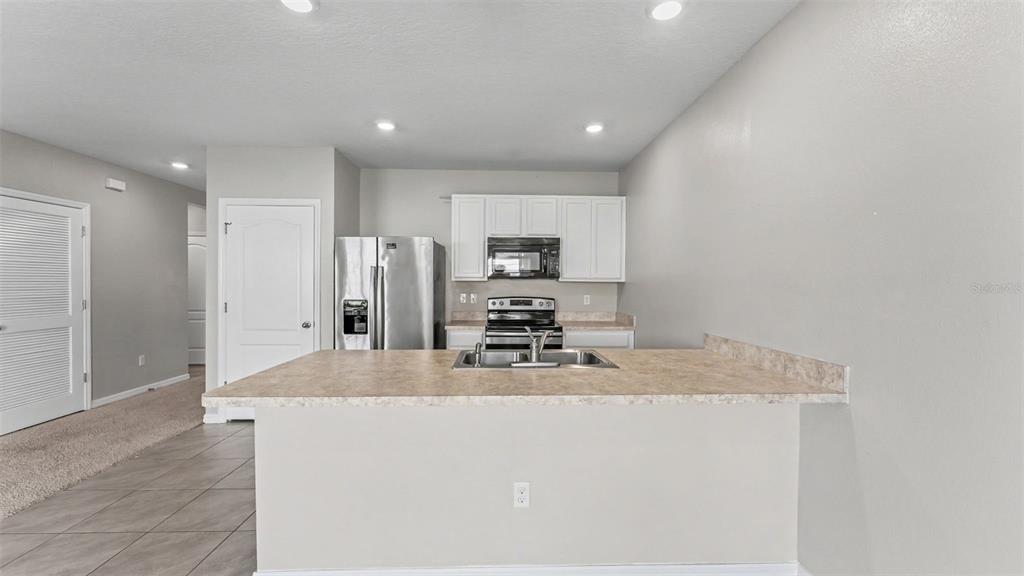 A kitchen features a breakfast bar, stainless steel appliances, and white cabinets — 524 BURNHAM CIRCLE, AUBURNDALE, FL
