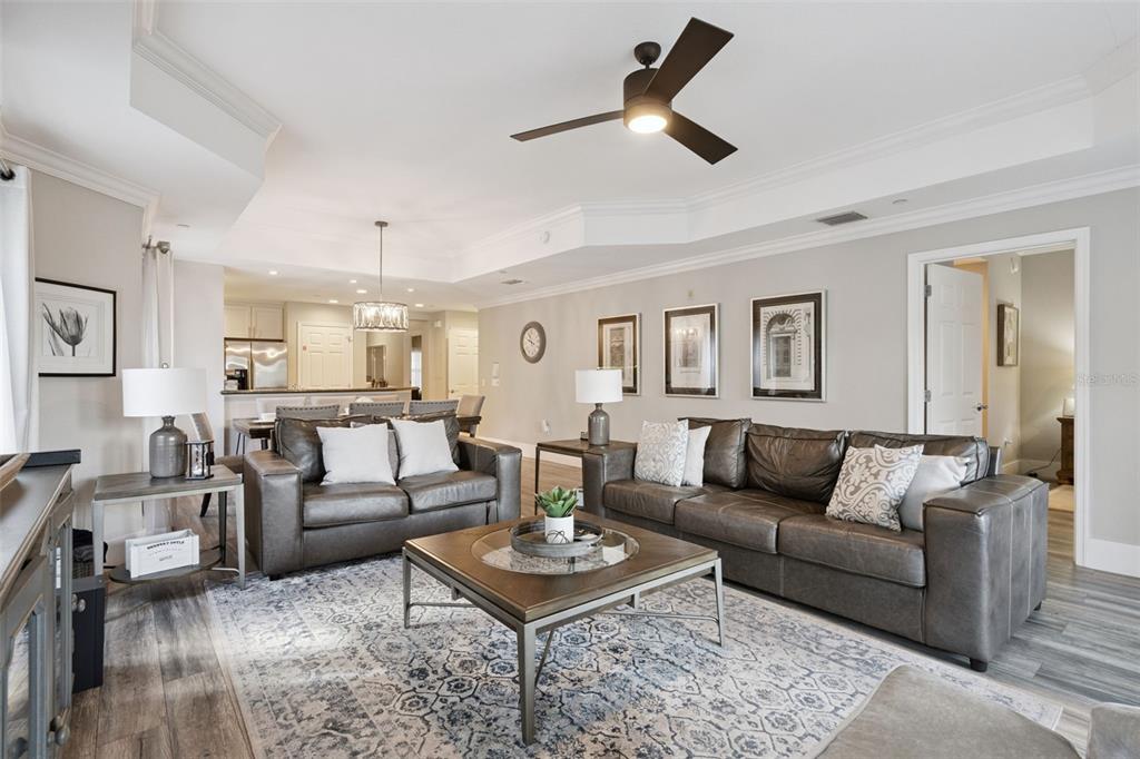 A living room features dark leather sofas, a coffee table, and a ceiling fan — 7651 WHISPER WAY UNIT 204, REUNION, FL