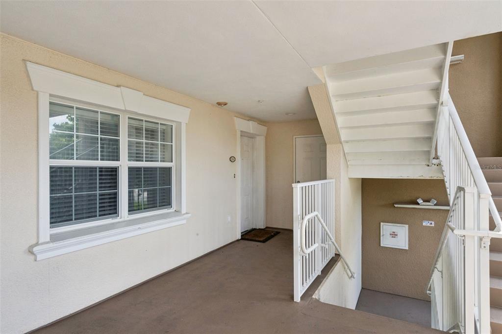 An outdoor landing features a window, a white door, and a staircase with white railings — 7651 WHISPER WAY UNIT 204, REUNION, FL