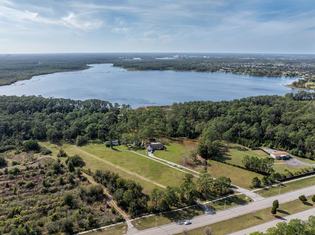 An aerial view shows a large lake behind a grassy property with several houses — 8834 WINTER GARDEN VINELAND ROAD, ORLANDO, FL
