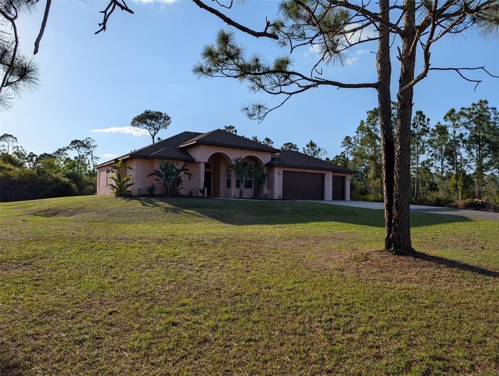 A single-story peach-colored house with a brown roof and garage sits on a grassy lot — 8511 AUSTRIAN BOULEVARD, PUNTA GORDA, FL