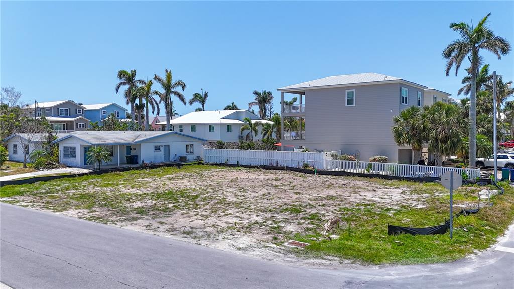 A vacant, sandy residential lot sits next to a white fence and several houses — 6406 HOLMES BOULEVARD, HOLMES BEACH, FL