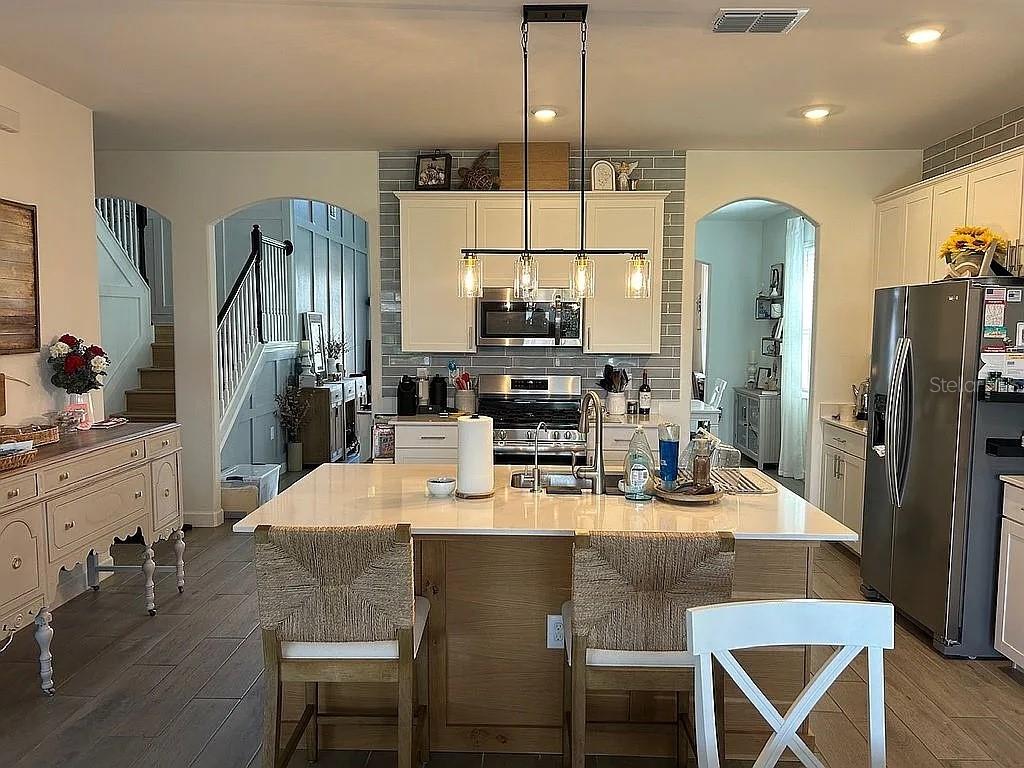 A bright entryway leads into a living room with gray furniture and wood-look tile floors — 15008 MISTY WATER CROSSING, BRADENTON, FL