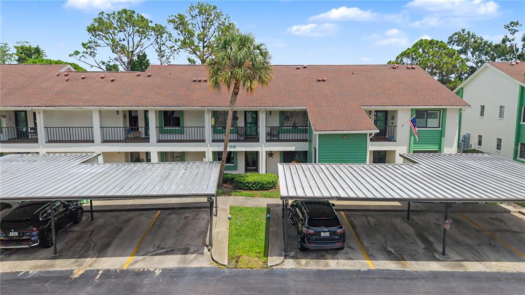 An exterior view of a two-story apartment building with covered parking spaces in front — 2543 ROYAL PINES CIRCLE UNIT 17K, CLEARWATER, FL
