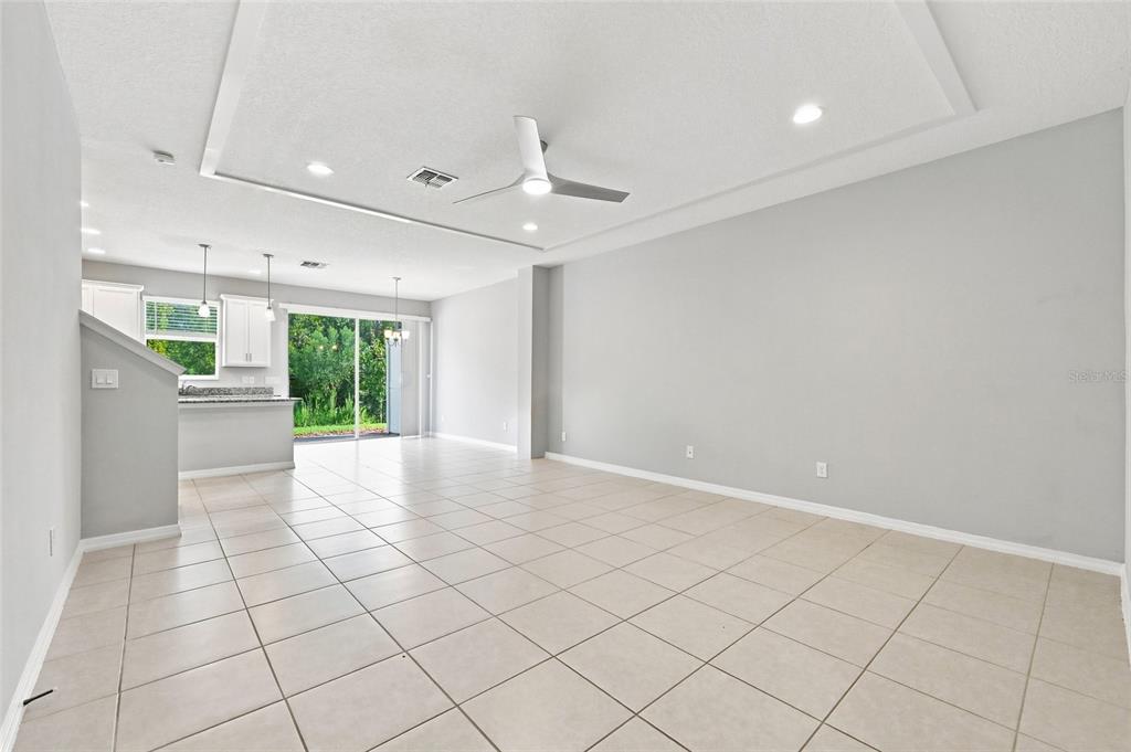 An open-concept living area features light tile flooring, gray walls, and a modern ceiling fan — 2559 SEDGE GRASS WAY, ORLANDO, FL