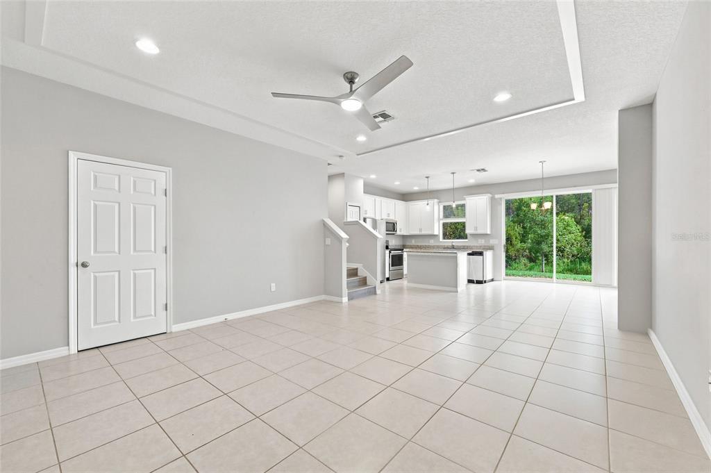 An open-concept living area with tile flooring, a ceiling fan, and an adjacent white kitchen — 2559 SEDGE GRASS WAY, ORLANDO, FL