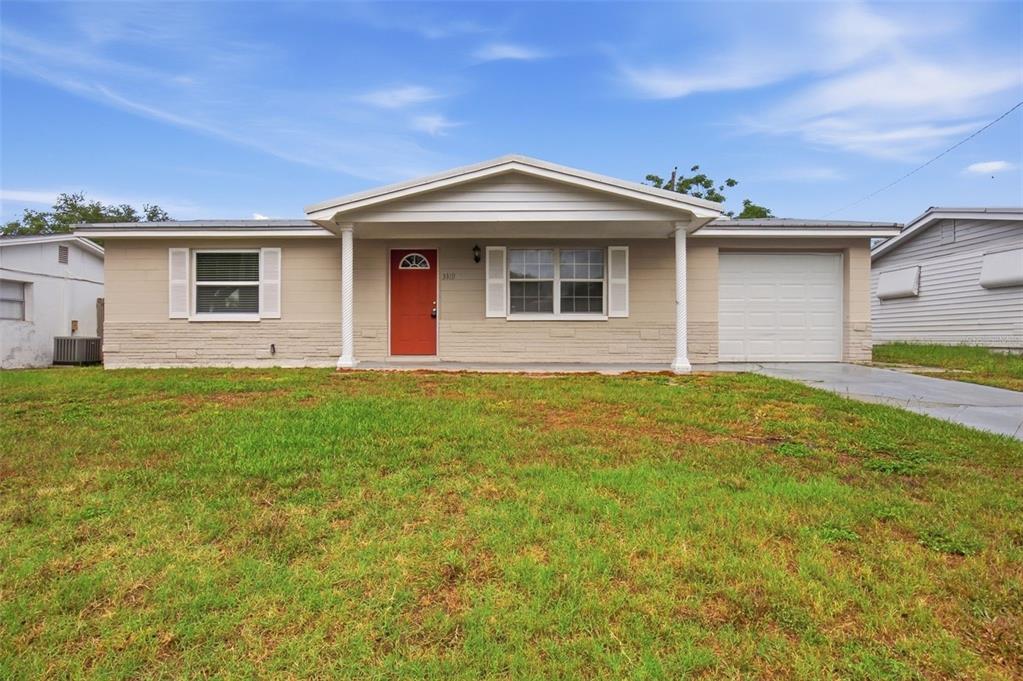 A single-story house with a beige exterior, a red front door, and an attached garage — 3319 CANTRELL STREET, HOLIDAY, FL