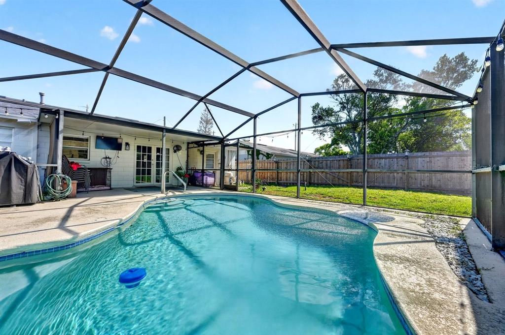 A screened-in swimming pool sits on a concrete patio behind a house with a fence — 880 SEMINOLE AVENUE, LONGWOOD, FL