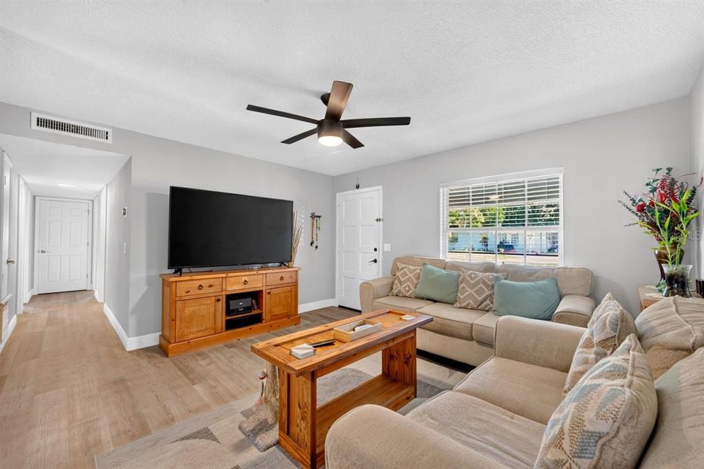 A living room features light wood flooring, a ceiling fan, a television console, and sofas — 880 SEMINOLE AVENUE, LONGWOOD, FL