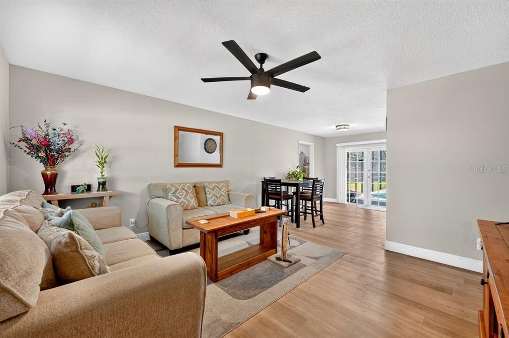 A living room with a beige sofa, wooden coffee table, ceiling fan, and dining area — 880 SEMINOLE AVENUE, LONGWOOD, FL