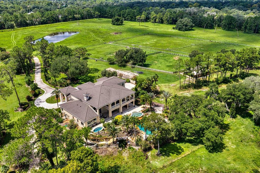 An aerial view of a large house with a pool, driveway, and surrounding pasture land — 7850 FOUR PINES ROAD, PLANT CITY, FL