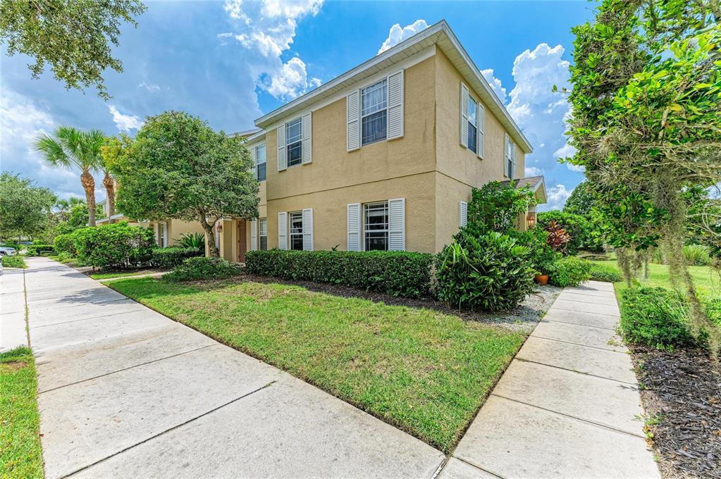 A two-story tan stucco townhouse with white shutters and a landscaped front yard — 14922 AMBERJACK TERRACE UNIT 106, BRADENTON, FL
