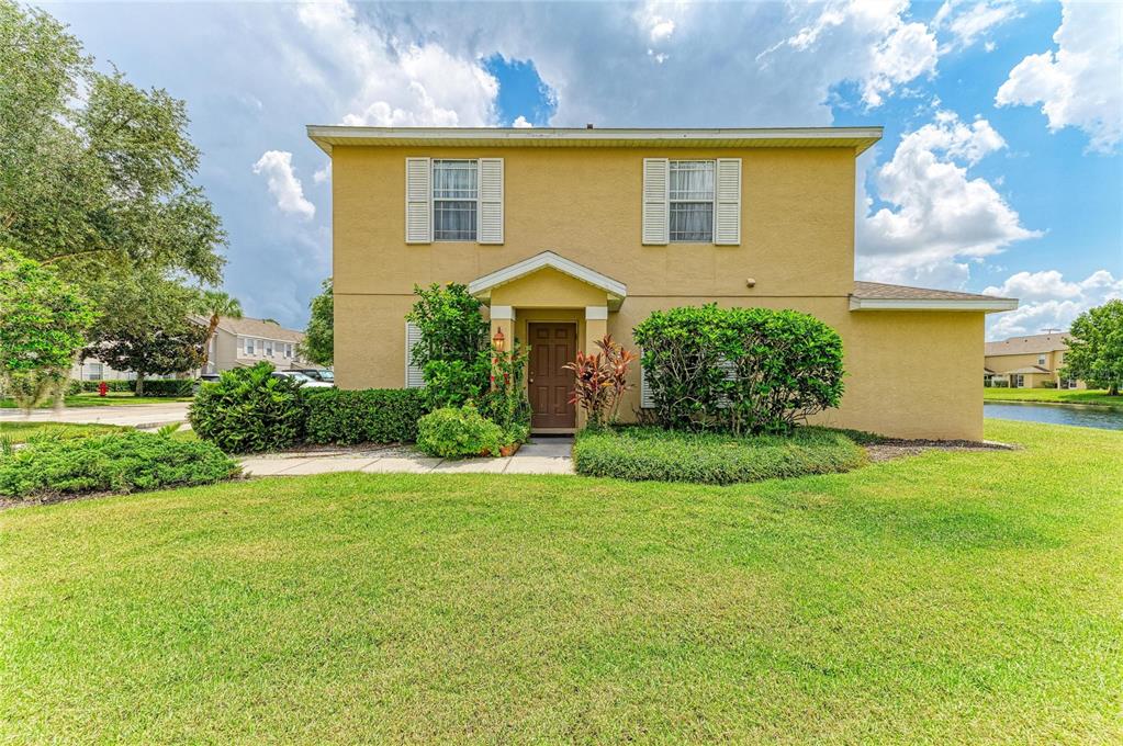 A two-story tan house with a front entrance, shutters, and a green lawn — 14922 AMBERJACK TERRACE UNIT 106, BRADENTON, FL