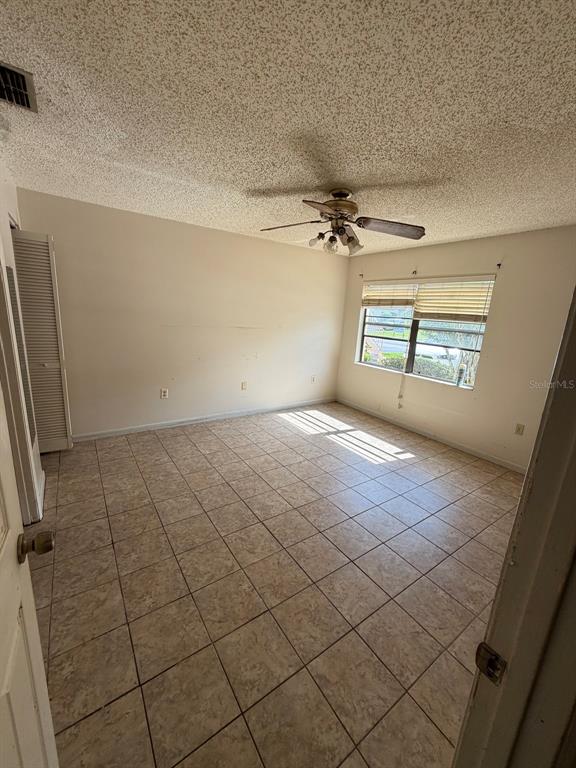 An empty bedroom features beige tile flooring, a ceiling fan, and a window with blinds — 6088 TOPHER TRAIL, MULBERRY, FL