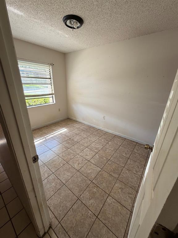A small bedroom with beige tile flooring, a single window, and a ceiling light fixture — 6088 TOPHER TRAIL, MULBERRY, FL