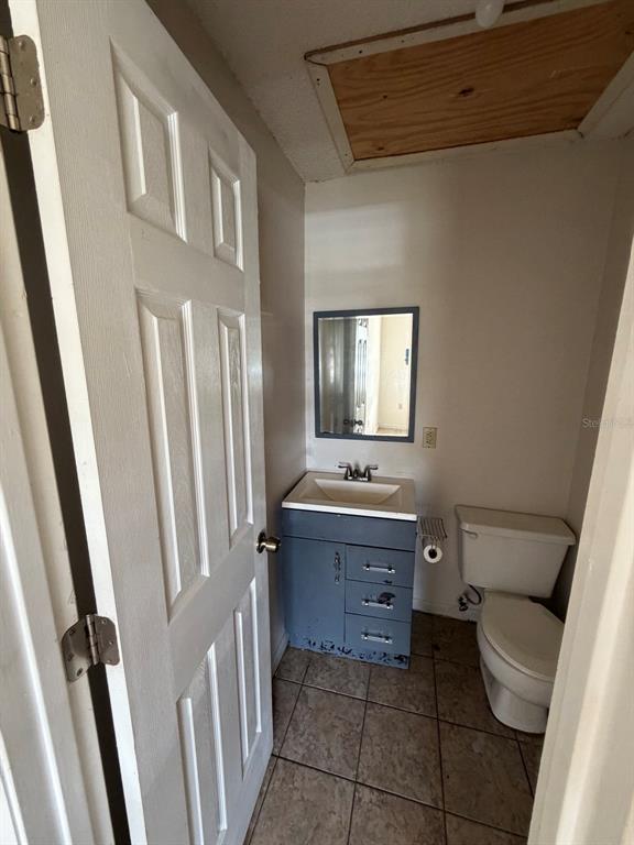 A small bathroom features a grey vanity, a wall mirror, a toilet, and tiled flooring — 6088 TOPHER TRAIL, MULBERRY, FL
