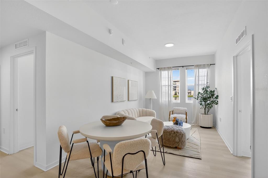 A bright living and dining area features light wood floors, white walls, and modern furniture — 5579 MILLENIA PARK BOULEVARD UNIT 402, ORLANDO, FL