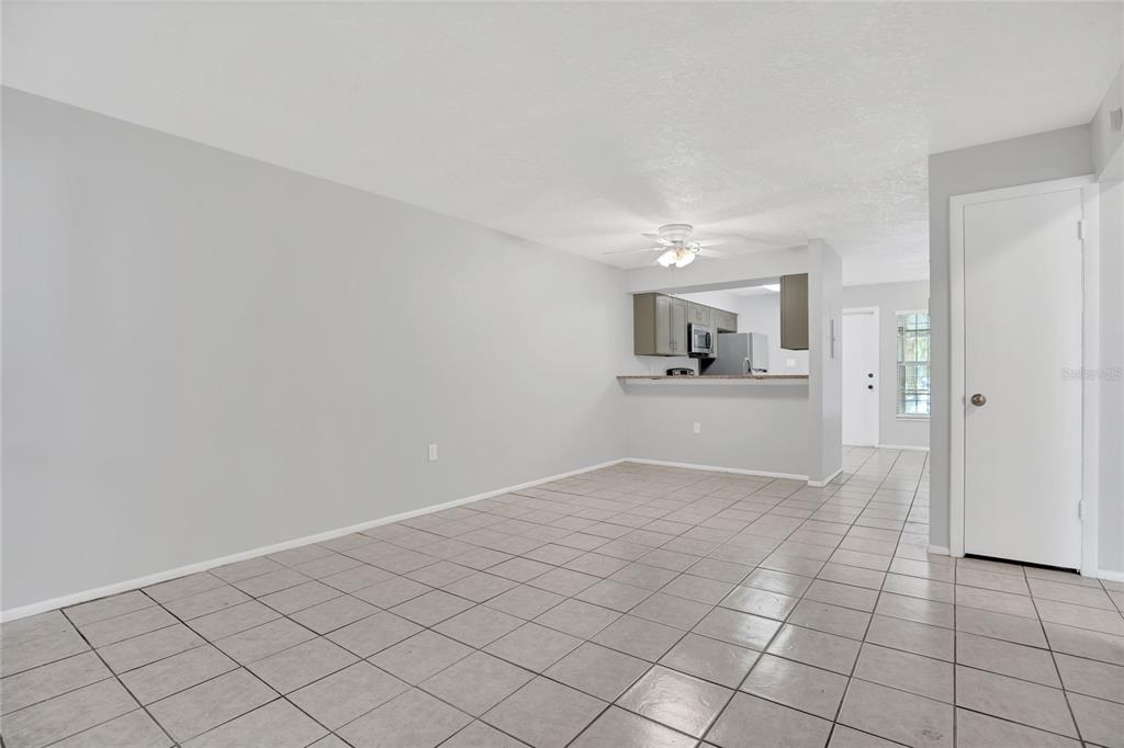 An open-concept living area features light gray walls, neutral tile flooring, and a kitchen pass-through — 2801 WILLOW RUN, ORLANDO, FL
