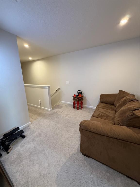 A carpeted loft area features a brown sofa, a small decorative table, and a staircase — 1871 HOLDEN RIDGE LANE, MINNEOLA, FL