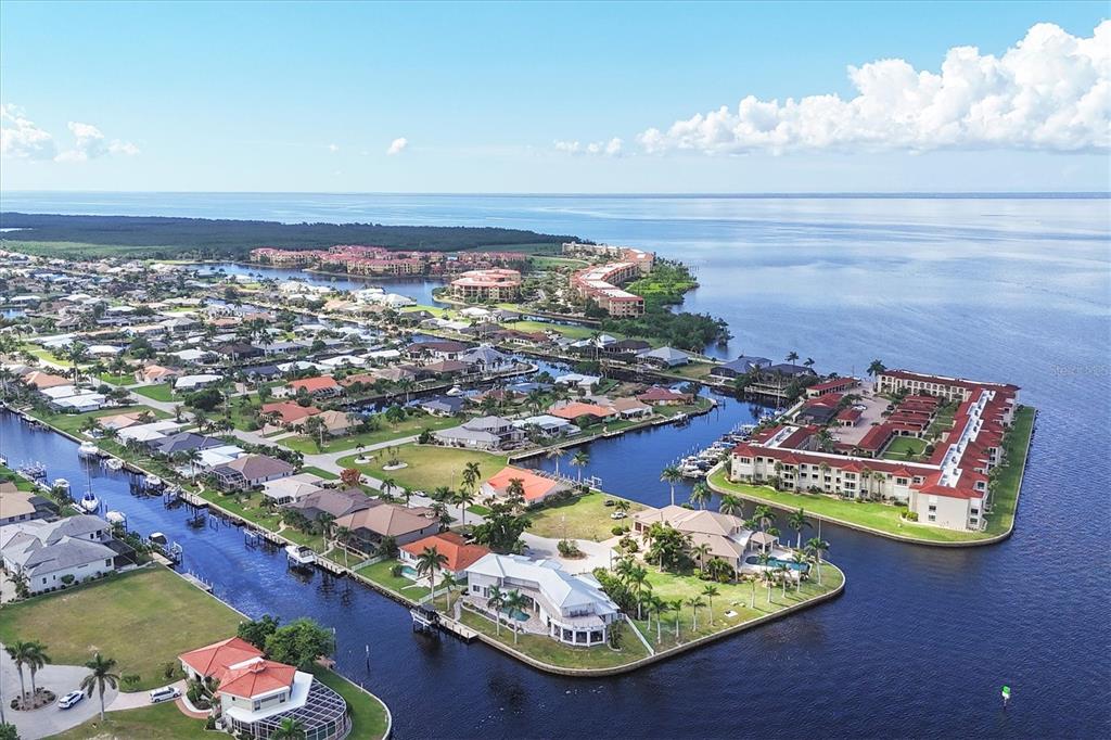 An aerial view shows waterfront homes and apartment complexes situated along canals leading to a bay — 7 HIBISCUS DRIVE, PUNTA GORDA, FL