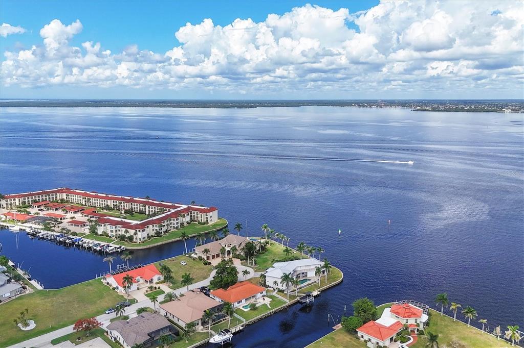An aerial view shows waterfront homes, a marina, and a large apartment complex along a bay — 7 HIBISCUS DRIVE, PUNTA GORDA, FL